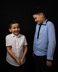 Two boys on a black background are brothers. they look at each other.Senior and junior.A child's smile