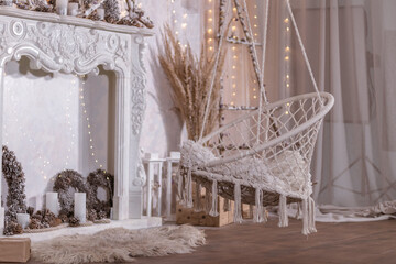 Festive New Year's white interior with wicker hanging chair and fireplace