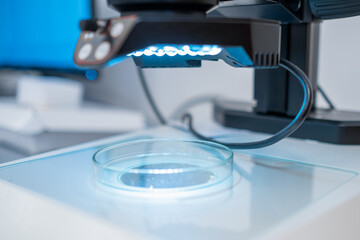 A modern electronic microscope for examing samples in Petri dish in the biochemical or medical laboratory.