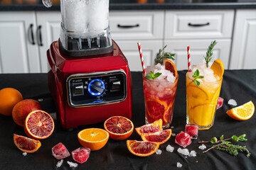 Close-up of homemade citrus lemonade in faceted glasses. Red blender on the kitchen countertop....