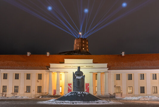 Vilnius Light Festival. National Museum of Lithuania and Gediminas statue and tower or castle in winter with snow and laser lights in the sky