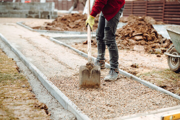 Worker using pavement slabs and shovel to build stone sidewalk. Close up of construction worker...