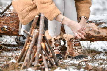 Girl tying her shoe laces in a snowy forest
