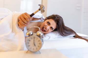 Young woman tries to break the alarm clock with hammer, Destroy the Clock. Girl lying in bed...