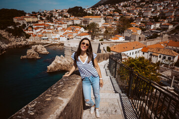 Fototapeta na wymiar Laughing young woman tourist walking on the city walls of dubrovnik in croatia. Travel photography