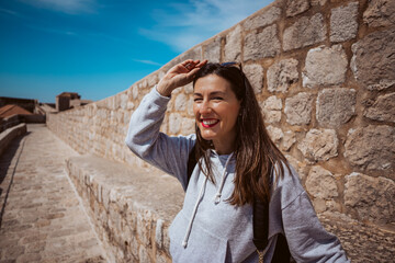 Laughing young woman tourist walking on the city walls of dubrovnik in croatia