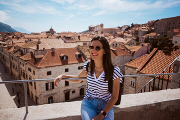 Fototapeta premium Laughing young woman tourist walking on the city walls of dubrovnik in croatia