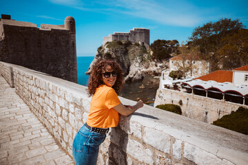 Fototapeta premium Laughing young woman tourist walking on the city walls of dubrovnik in croatia