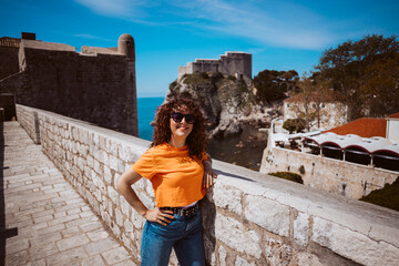 Fototapeta premium Laughing young woman tourist walking on the city walls of dubrovnik in croatia
