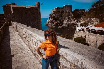Fototapeta premium Laughing young woman tourist walking on the city walls of dubrovnik in croatia