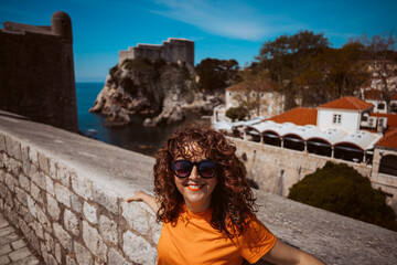 Fototapeta premium Laughing young woman tourist walking on the city walls of dubrovnik in croatia