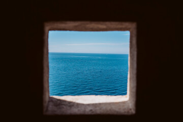.Small stone window overlooking the Mediterranean Sea. Relaxing view of the blue sea.