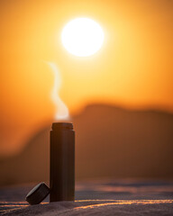 Hot tea in a termos during a cold winter sunrise