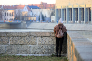 Kobieta stoi nad rzeką Odrą we Wrocławiu. - obrazy, fototapety, plakaty