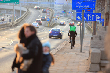 Kurier jedzie na rowerze we Wrocławiu, dostarcza jedzenie. 