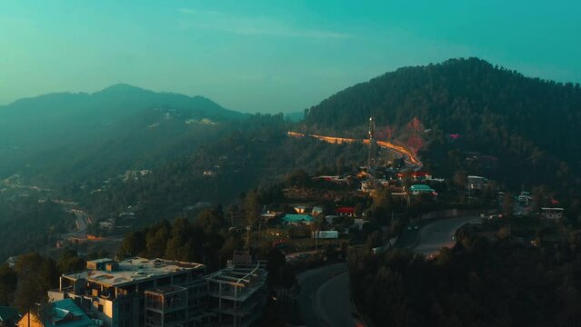 Aerial view of a village in green hills surrounded by trees in Murree, Pakistan