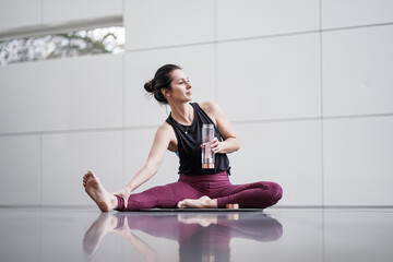 happy natural brown hair woman drinking bottle of water after yoga pilates fitness workout
