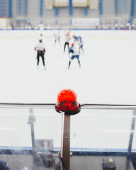 View of red warning light in focus - puck faceoff at the start of a hockey game