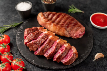 Two grilled picanha steaks with spices on a stone background