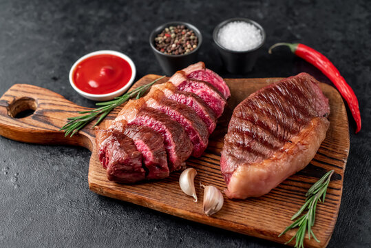 Two grilled picanha steaks with spices on a stone background
