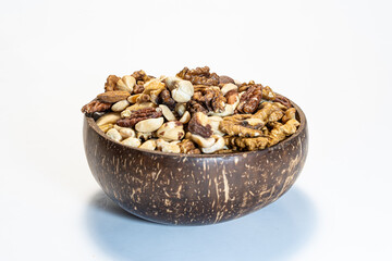 Nuts mix in a wooden bowl of coconut on a white background