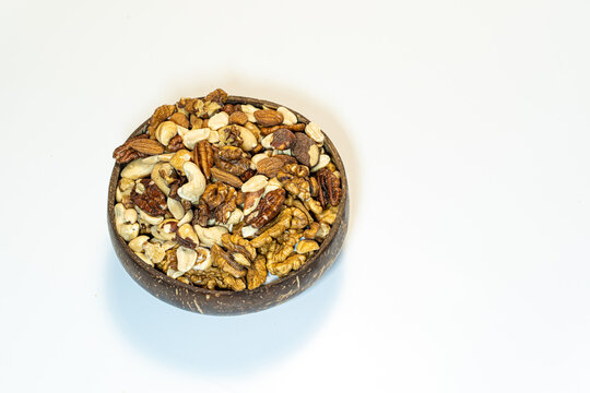 Nuts mix in a wooden bowl of coconut on a white background