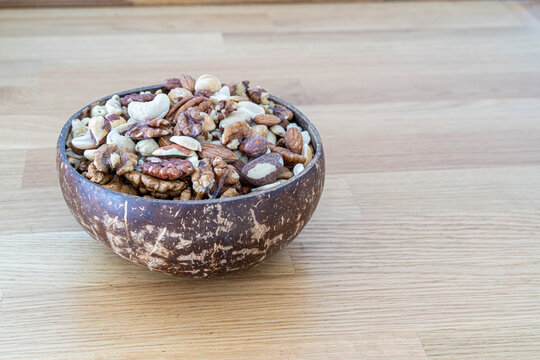Nuts mix in a wooden bowl made of coconut on a wooden background