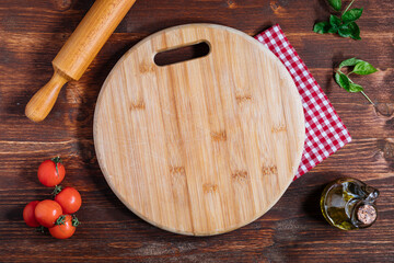 Pizza Napoletana, traditional and authentic Italian pizza baked in wood fired oven. Margherita pizza with mozzarella cheese, tomato sauce, olive oil and basil leaves. On wooden board with ingredients.