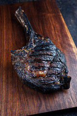 Modern style barbecue dry aged Chianina tomahawk steak served as close-up on a wooden design board