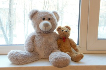 two teddy bears on the windowsill in a hug, the concept of sympathy and love