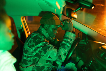 Young depressed african man thinks about problems in life while sitting in car with girlfriend at...