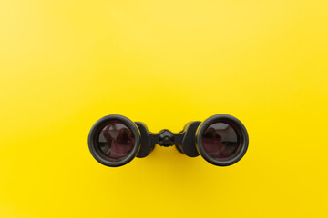 Binoculars on a light yellow background. Banner. Flat lay, top view.