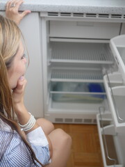 Woman is looking at empty fridge