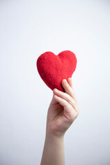 Fototapeta premium Child hand holding a red heart, white background. healthy life and love concept 