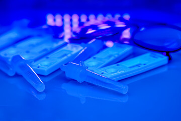 5 covid-19 antigen self-tests, buffer bottles and thin black-rimmed glasses on a light background...