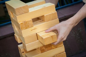 A falling tower game, hands holding wooden bars in close-up.