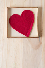 red felt heart in a shallow box on a wooden surface