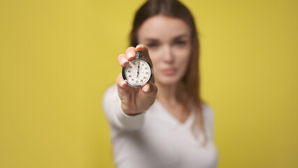 Stopwatch in foreground in hand of attractive young woman. stopwatch counts down from zero. Retro...