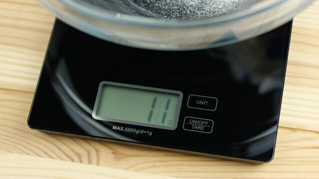 Kitchen scale with digital display measuring out grams of flour in a glass bowl