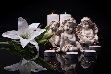 White angels with candles and white lily flower on a black background.