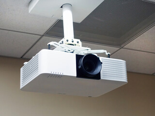 Multimedia projector hanging on the ceiling of conference room.