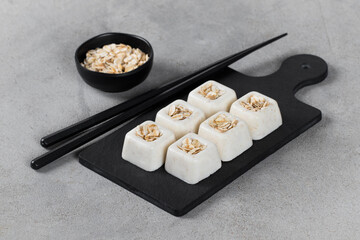 Small oatmeal cream dessert in the shape of a square savarin on a serving board on a light gray background