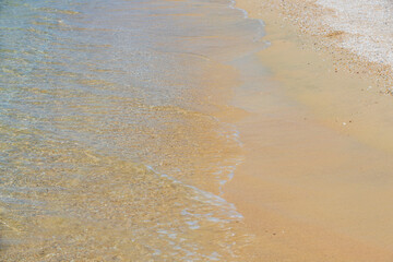 Beautiful nature backgrounds. Coastal sand is covered by oncoming wave. Greece