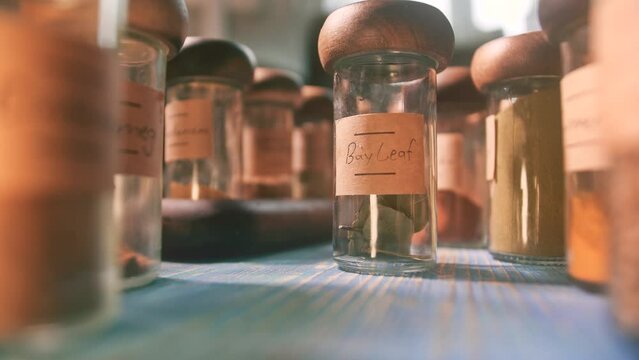 Putting bottle with bay leaf on the table among other spices