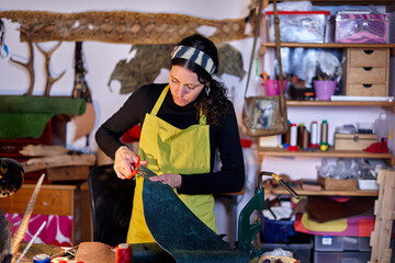 Craftswoman cutting leather