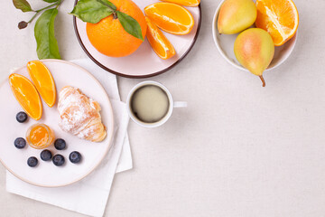 Breakfast with a cup of coffee, fresh croissant , jam and ripe blueberries and juicy oranges, pears on a white background, flat lay, copy space