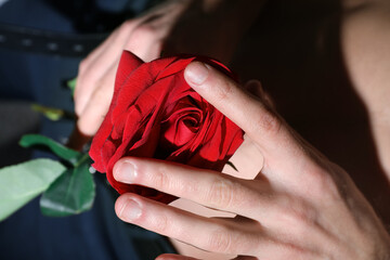 Young man holding red rose, closeup. Erotic concept