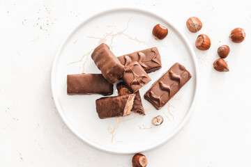 Plate with tasty chocolate nut bars on white background