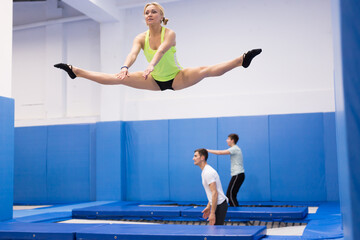Young sporty woman with friends practicing and jumping in trampoline center
