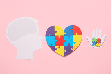 Colorful puzzle pieces in shape of heart, human head and palm on color background. Concept of autistic disorder